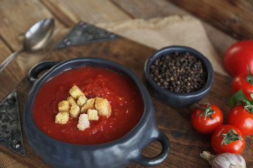 tomato soup with fresh herbs, clove, black pepper and crackers on rustic wooden background,  selective focus