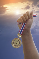 Fototapeta na wymiar hand show golden award, number 1, medal on sky background, concept in winner and champion