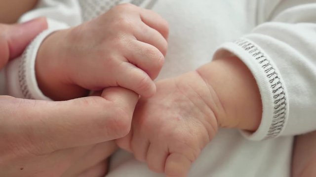 baby holds mother finger