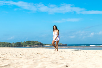 Colorful portrait of young attractive asian woman in sexy white dress on the tropical beach of Bali island, Indonesia.
