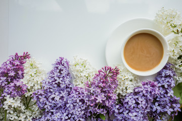 Obraz na płótnie Canvas Background with branches of lilac on a white-painted wooden boards and a Cup of coffee with milk Top view Copy space The theme of spring, summer, good morning