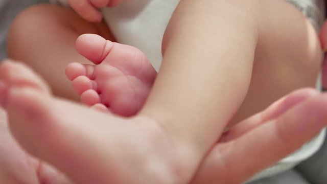 Mother keeps baby legs in her hands, closeup