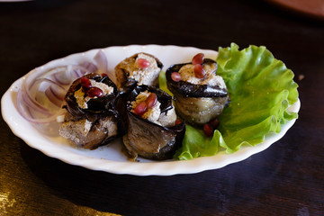 Vegan food. Baked stuffed eggplant with onions, lettuce and pomegranate seeds on white dish