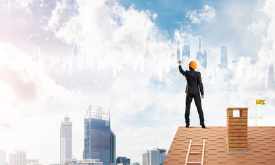 Man architect draw silhouette of modern city on blue sky. Mixed media