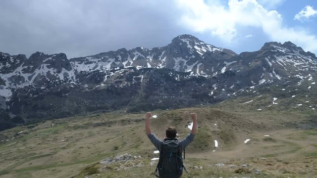 Hiker goes to the top and raises his arms up in victory gesture