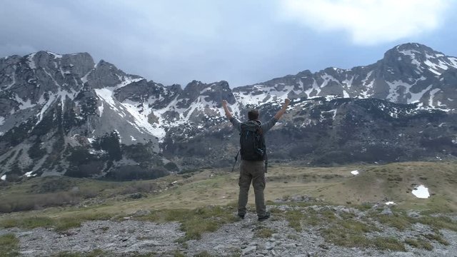 Hiker stands on top and keeps his hands raised in a gesture of victory