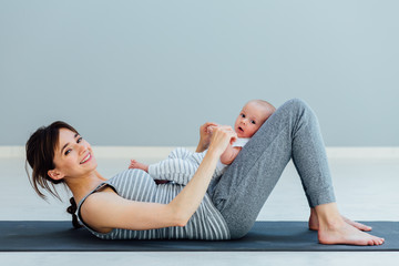Sport, motherhood and active lifestyle concept - side view of young mother workout together with...