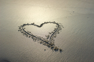 Heart drawn in sandy beach at sunset