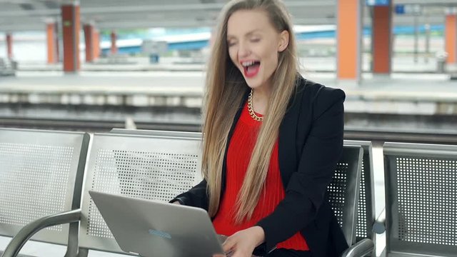 Elegant woman checking laptop and receives good news, steadycam shot
