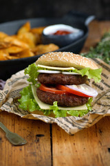 Homemade burger with potato slices on a wooden table, Rustic, Selective focus