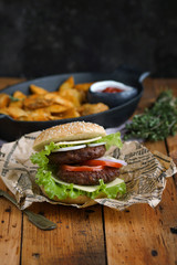 Homemade burger with potato slices on a wooden table, Rustic, Selective focus