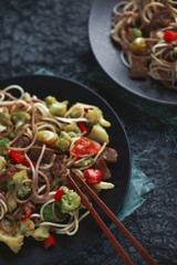 Asian food, Noodles with beef and vegetables on dark background, Top view, Selective focus, Vertical