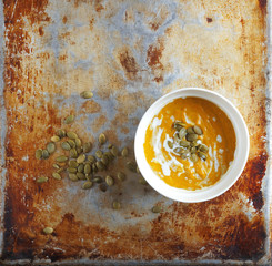 Colorful pumpkin soup and pumpkin seeds on an old baking sheet, Selective focus, Primitive kitchenalia
