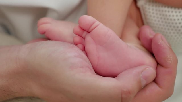 Baby legs in dad hands, closeup