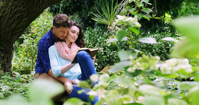 Romantic couple reading novel in park