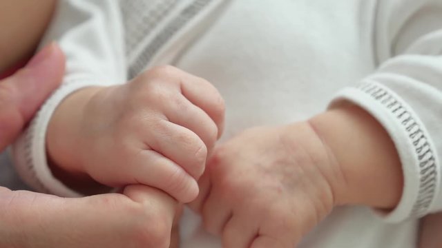 baby holds mother finger, closeup