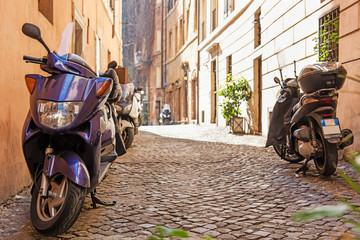Scooters parked on narrow cozy Rome cobblestone street. Italy