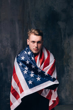 Man is covered by american flag on dark background. Patriot, national event celebration, pride, usa citizen concept
