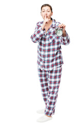 Girl with an alarm clock in checkered pajamas showing a gesture quieter on a white background