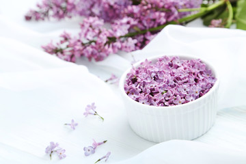 Lilac flowers in bowl on white cloth