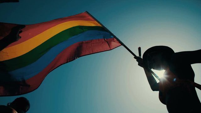 Slow motion shot of the pride flag waving high during a pride parade