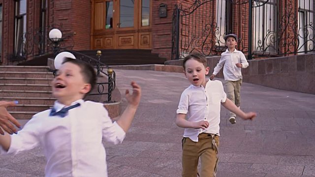Dear amicable children play on the street. Boys in white shirts run on the street
