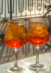 Waiter prepared the Aperol Sprits summer cocktail with Aperol, prosecco, ice cubes and orange in wine glass, ready to drink on sunny terrace
