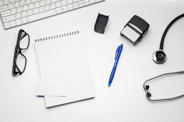 Top view of modern, sterile doctors office desk. Medical accessories isolated on a white table background with copy space around products. Photo taken from above.