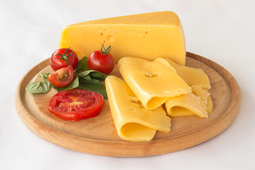 Cheese, tomato and green basil on a cutting board. White background.