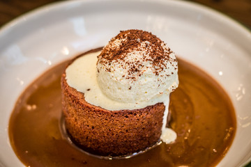 Date pudding with vanilla ice-cream dusted with cocoa powder