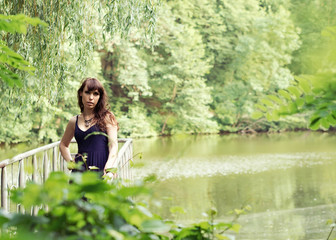 Beautiful woman in sundress on the pond bridge