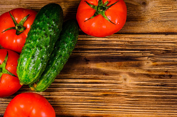 Ripe tomatoes and cucumbers on wooden table. Top view