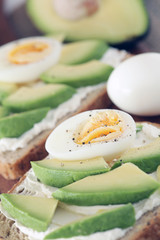 Avocado, cream cheese and boiled eggs on wholemeal bread - shallow dof