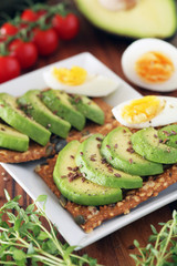 Avocado and boiled egg on pumpkin seeded crackers - shallow dof