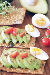 Avocado, boiled egg and tomato on pumpkin seeded crackers - shallow dof
