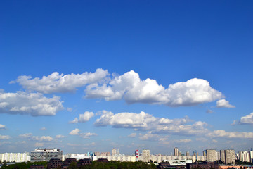 Fluffy clouds over the city in a clear sky