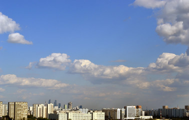 Fluffy clouds over the city in a clear sky