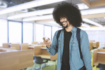 Afro guy looking at smartphone in classroom