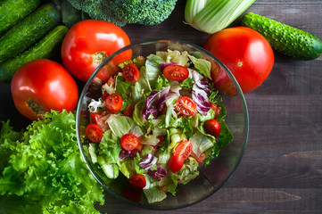 Greek salad in a glass bowl. Vegetarian salad. Juicy, fresh vegetables on the table. Cucumbers, tomatoes, lettuce. Stylish, juicy background of fresh vegetables.