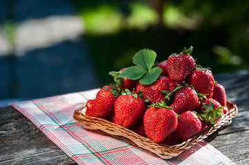Juicy strawberries in a wicker basket, wooden table, against the backdrop of a beautiful background...