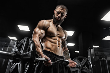 Fototapeta na wymiar Attractive tall muscular bodybuilder doing heavy deadlifts in moder fitness center.