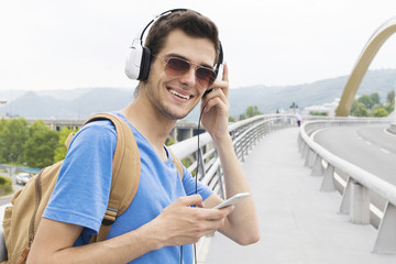 young man with the headset and the phone in the city