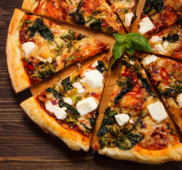 Pizza with feta cheese and spinach on wooden table