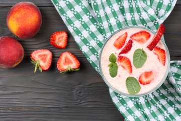  Healthy strawberry yogurt with peach and mint leaves and fresh berries on dark wooden background. Top view with copy space.