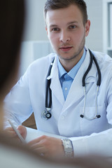 Handsome young male doctor talking to patient at office.  Healthcare and medical concept.