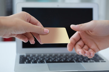 Closeup shot of a woman's hand  giving a payment credit card to the seller in computer store. Girl holding a credit card. Shallow depth of field with focus on the credit card.