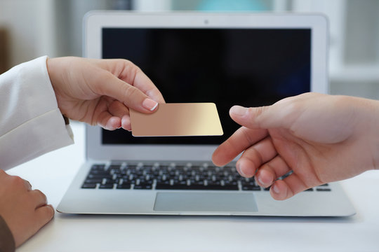 Closeup shot of a woman's hand  giving a payment credit card to the seller in computer store. Girl holding a credit card. Shallow depth of field with focus on the credit card.