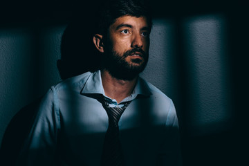 Fototapeta premium Businessman or political prisoner in dark cell. Concept of white collar crime