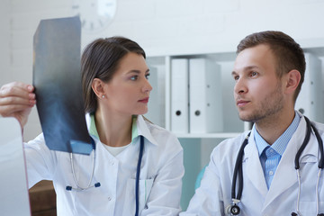 Male and female doctors discussing x-ray image.