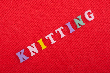 Knitting. Knitted Fabric Texture. Word composed from ABC alphabet letters on red background.